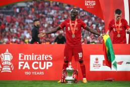 Sadio Mane celebrating with the FA Cup trophy and the Senegalese flag.